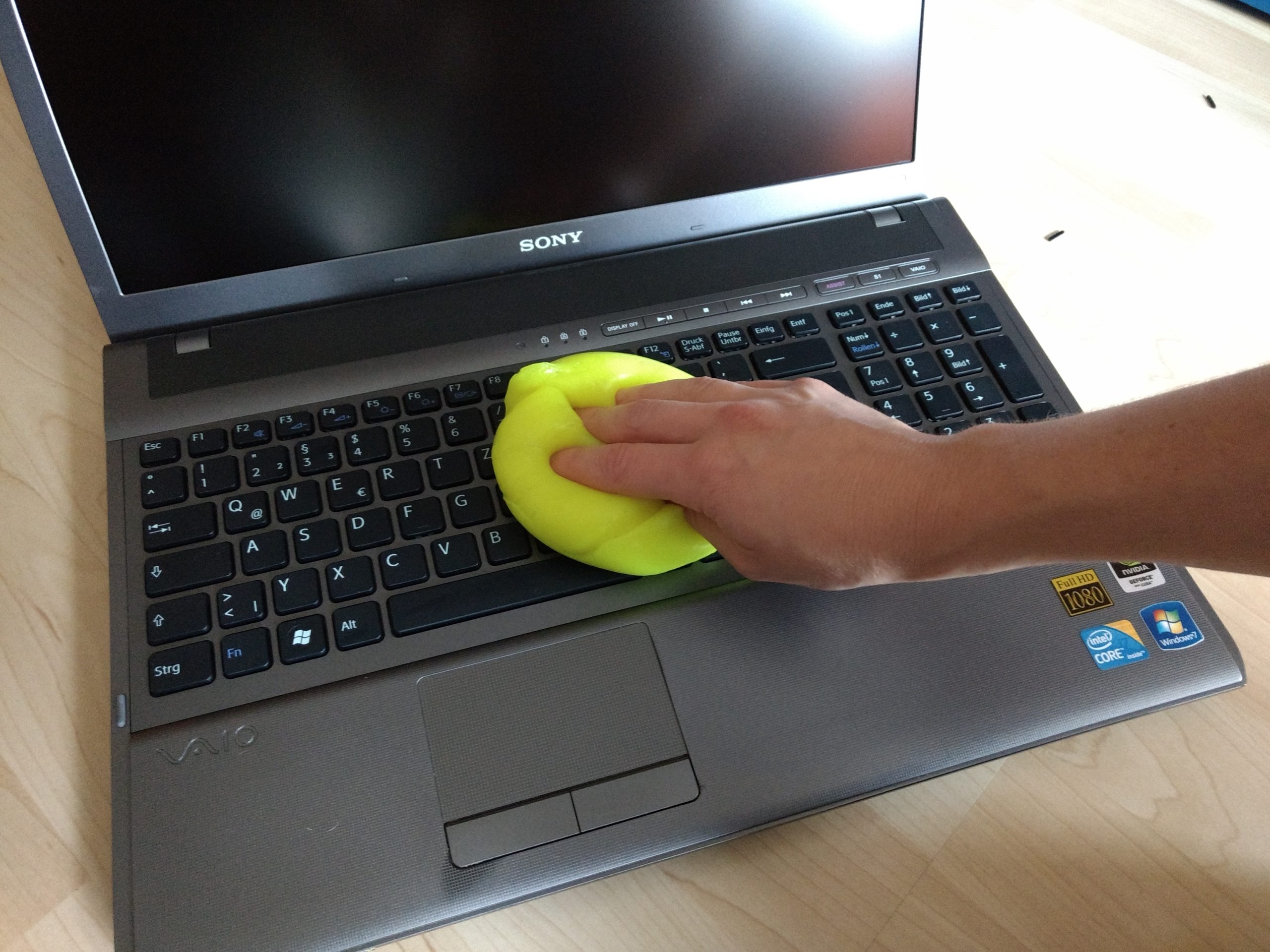 Die Tastatur eines SONY-Laptops wird mit einer gelben Reinigungsmasse gesäubert und desinfiziert.