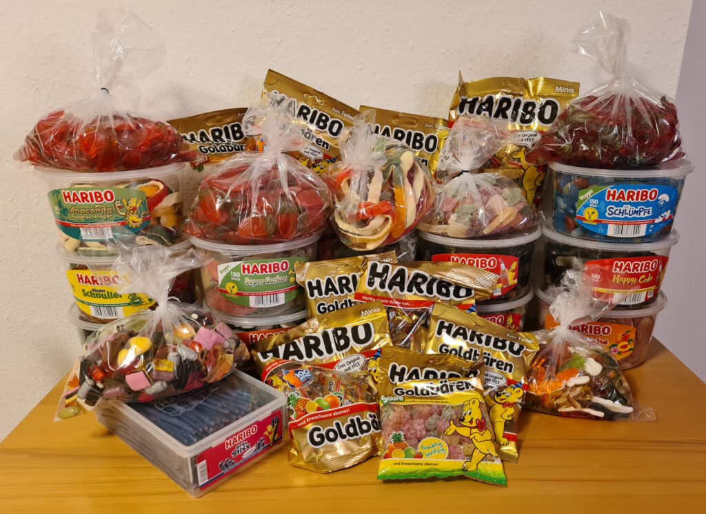 Auf einem Tisch befinden sich über ein Dutzend Dosen und mehrere Tüten mit Süßigkeiten der Firma „HARIBO“.