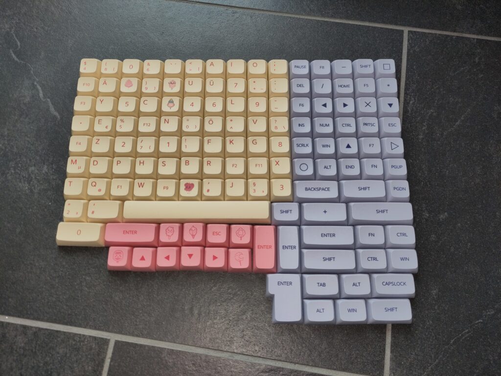 Foto vieler Tastenkappen in Pastellfarben (crème, rosa, blau). Auf manchen sind Süßigkeiten abgebildet.