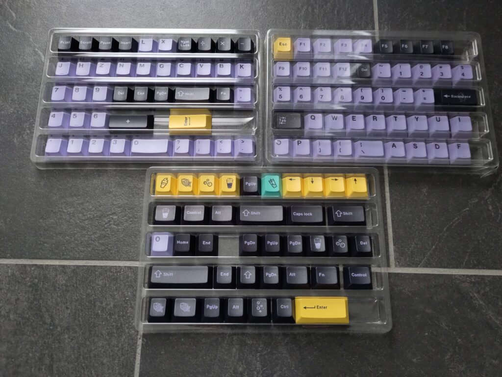 Foto vieler Tastenkappen in unterschiedlichen Farben (lila, gelb, schwarz, türkis). Auf manchen sind Nahrungsmittel abgebildet.