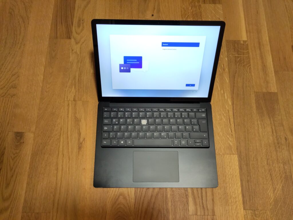 Foto des aufgeklappten Laptops, welcher den Einrichtungsmodus anzeigt. Die Taste fehlt und ansonsten ist das Gerät in einem optisch relativ guten Zustand.