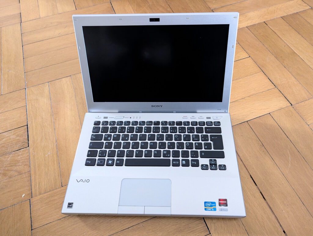Foto des aufgeklappten Laptops. Es befindet sich in einem optisch guten Zustand.