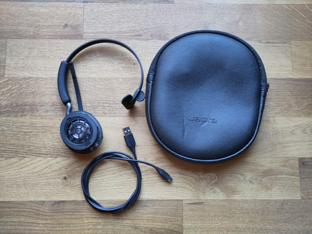 Foto des Monoheadsets mit fehlendem Ohrpolster, USB-A-auf-C-Kabel und Transporttasche.