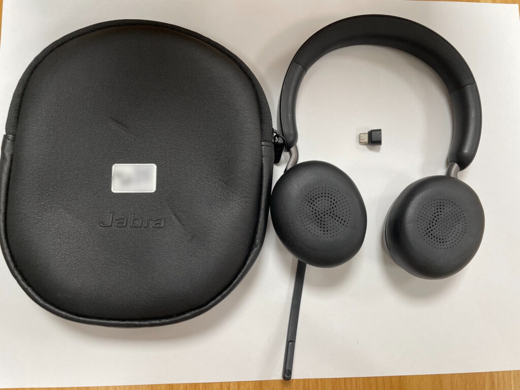 Schwarzes Jabra-On-Ear-Headset mit Mikrofonarm, kleinem USB-Dongle und schwarzem Transportetui.
