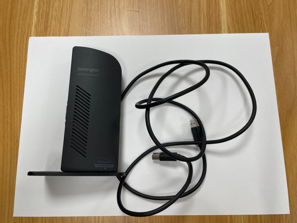 Schwarze Kensington-USB-3.0-Dockingstation mit Standfuß und zwei angeschlossenen USB-Kabeln auf weißem Hintergrund.