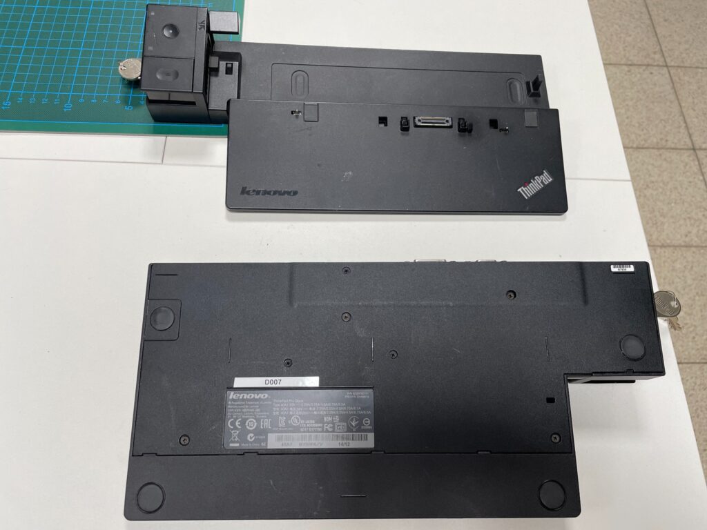 Drei schwarze Lenovo ThinkPad Pro Dockingstationen mit seitlichen Verriegelungen und Schlüsseln liegen auf einem Tisch.
