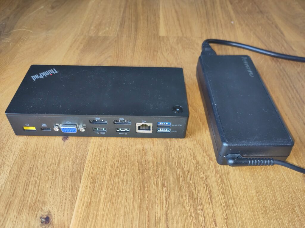 Foto des Docks und des passenden Netzteils. Beides befindet sich in einem hervorragenden Zustand.