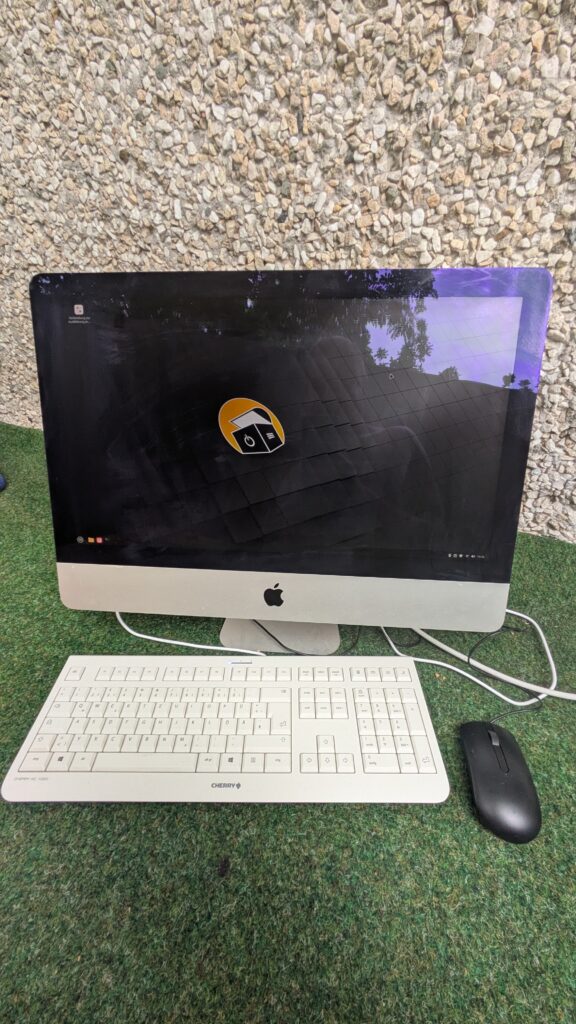 Foto des Computers mit Anzeige des Linux Mint Desktops, einer Tastatur und Maus.